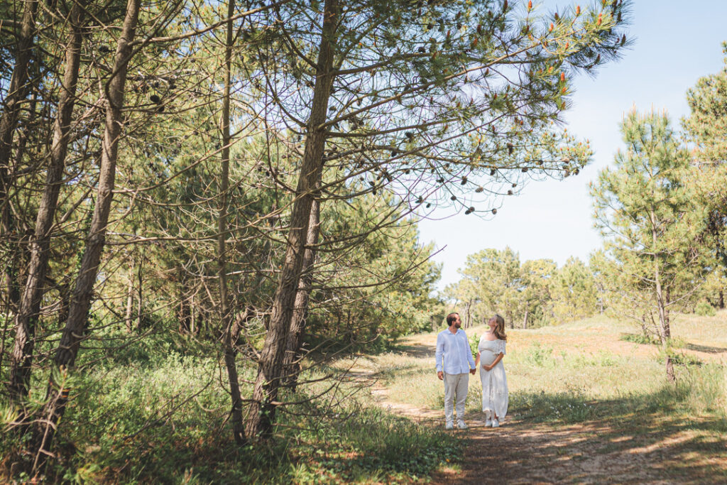Photo de couple enceinte en lumière naturelle sous les pins à Biville